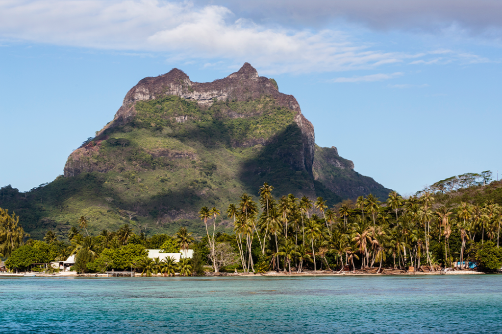 Pacific Ocean, French Polynesia, Society Islands, Leeward Islands, Bora Bora. View of extinct volcano and peaks of Mount Otemanu and Mount Pahia above palms.