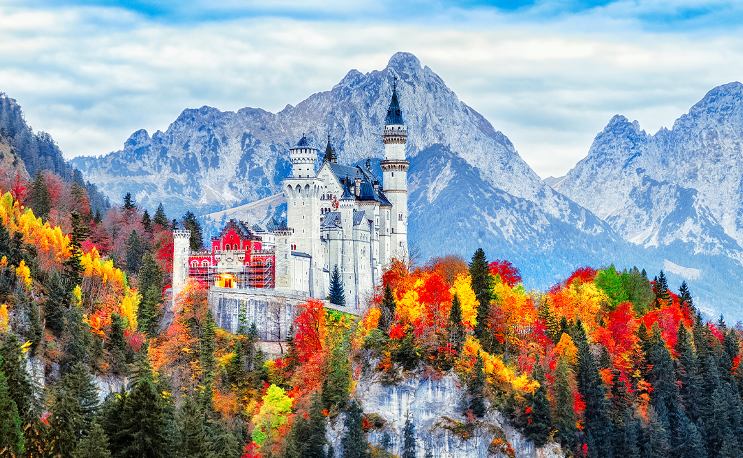 Neuschwanstein medieval castle in Germany, Bavaria land. Beautiful autumn scenery of Neuschwanstein ancient castle circled by colorful tree, amazing seasonal fall scene. Famous and popular landmark.