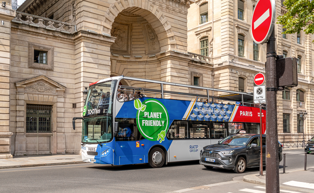 Paris, France - August 08, 2023: Tootbus tour bus OpenTour company in front of the police prefecture building (Caserne de Garde de Paris). Planet Friendly Ratp: environmentally buses electricity
